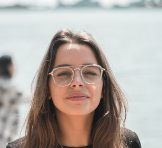 Woman with glasses standing outdoors near water